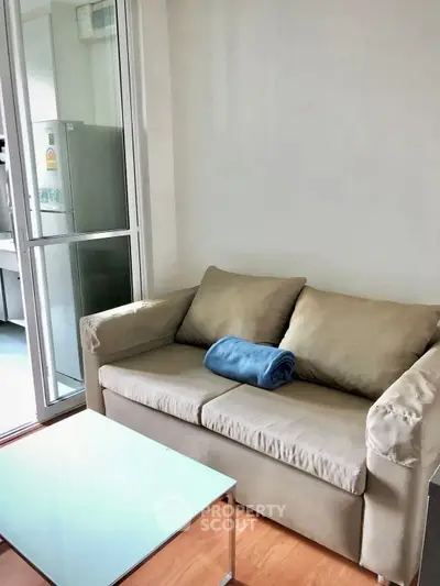 Cozy living room with beige sofa and glass coffee table in modern apartment.