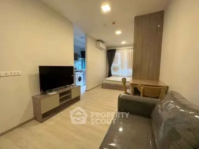 Modern living room with TV, sofa, and dining area in open-plan apartment.