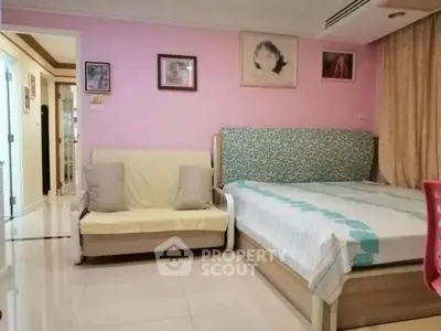 Cozy bedroom with pastel pink walls, featuring a bed and a small sofa, perfect for relaxation.