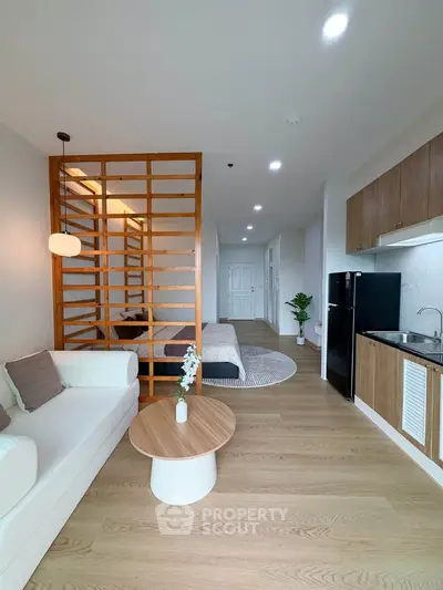Modern open-layout living room with stylish wooden partition and sleek kitchen area.
