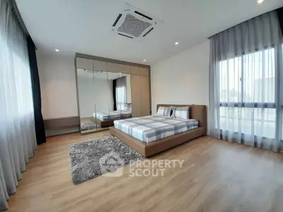 Spacious modern bedroom with mirrored wardrobe and large windows