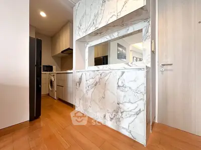 Modern kitchen with marble accents and wooden flooring, featuring a washing machine and sleek appliances.