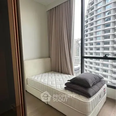 Cozy bedroom with city view, featuring a single bed and large window.