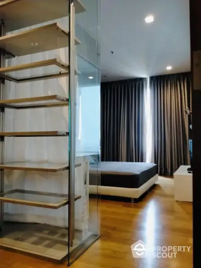 Modern bedroom with glass shelving and wooden flooring, featuring elegant curtains and ambient lighting.