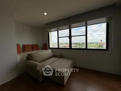 Cozy living room with sofa and panoramic city view through large window.