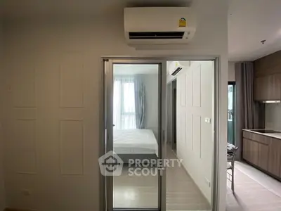 Modern apartment interior with sliding glass doors and air conditioning, featuring a cozy bedroom and sleek kitchen.