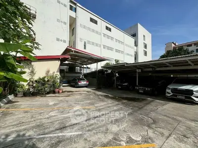 Spacious parking area in residential building with multiple cars parked under shade.