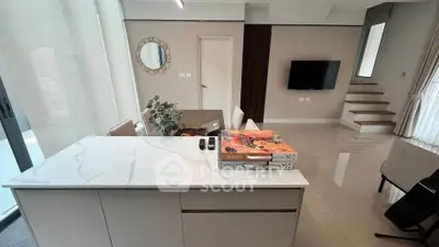 Modern living room with sleek design and open layout, featuring a stylish kitchen island and elegant decor.