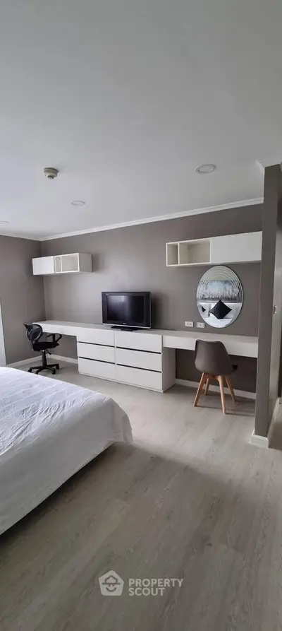 Modern bedroom with sleek furniture and workspace, ideal for comfort and productivity.