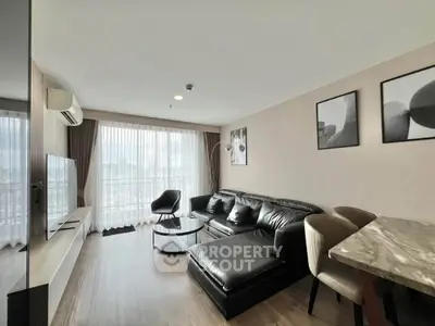 Modern living room with sleek black leather sofa and panoramic city view.
