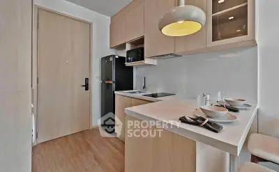 Modern kitchen with sleek cabinetry and breakfast bar in compact apartment.