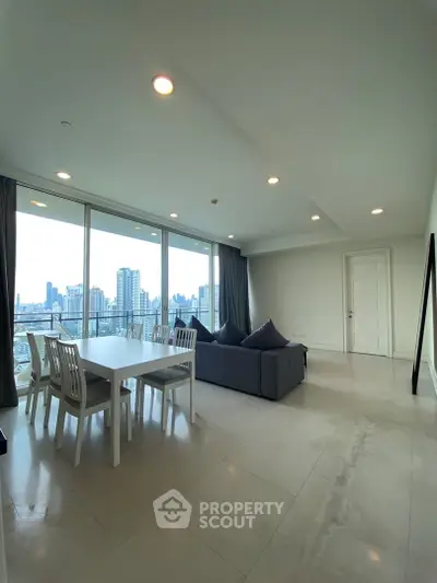 Spacious modern living room with city view, featuring sleek furniture and large windows for natural light.