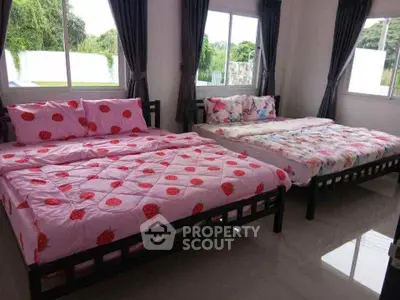 Spacious bedroom with two cozy beds and large windows offering natural light.