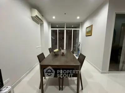 Modern dining room with sleek table and chairs, featuring a minimalist design and air conditioning.