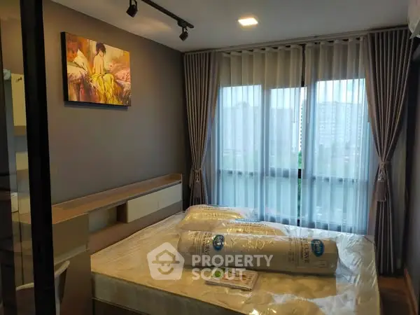 Modern bedroom with large window and stylish decor in urban apartment.