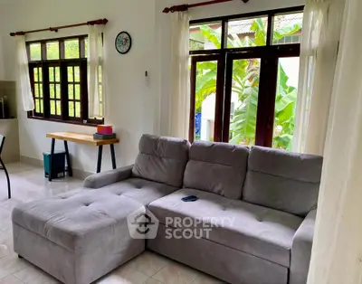 Cozy living room with large windows and plush gray sectional sofa, perfect for relaxation.