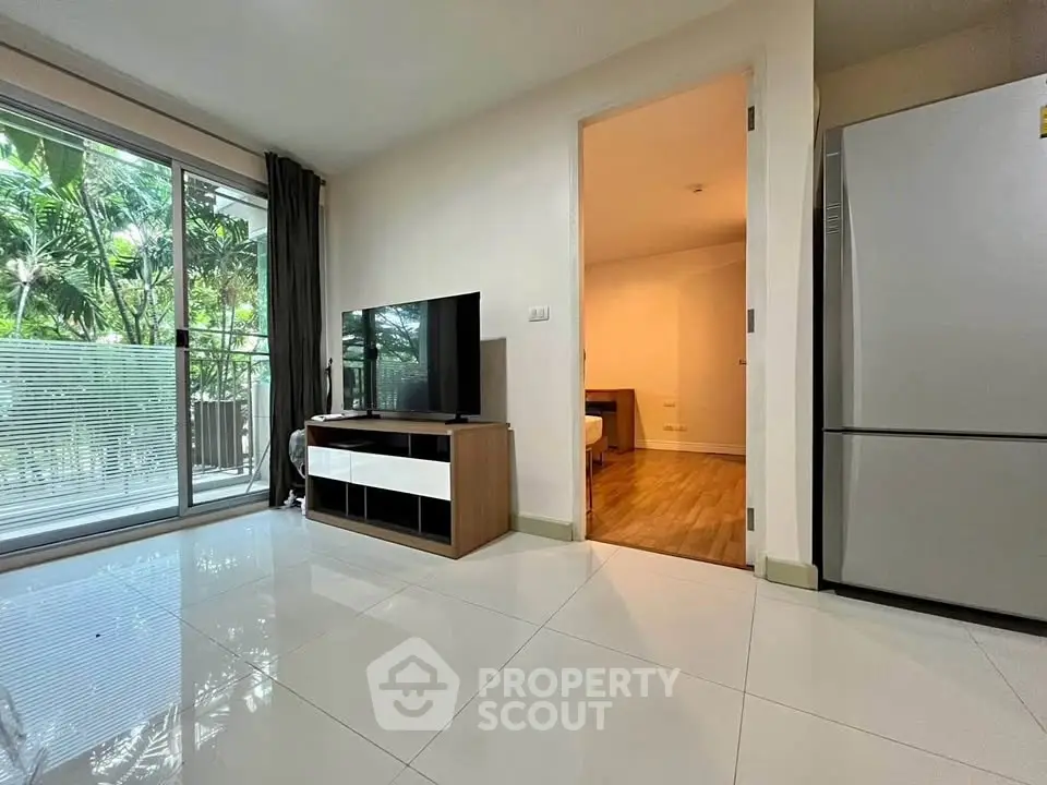 Modern living room with sleek TV unit and large window overlooking lush greenery.