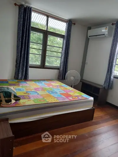 Cozy bedroom with colorful bedding, air conditioning, and large window view.
