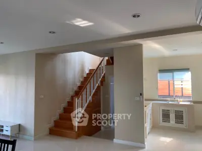 Spacious modern living area with wooden staircase and open kitchen layout, perfect for family gatherings.