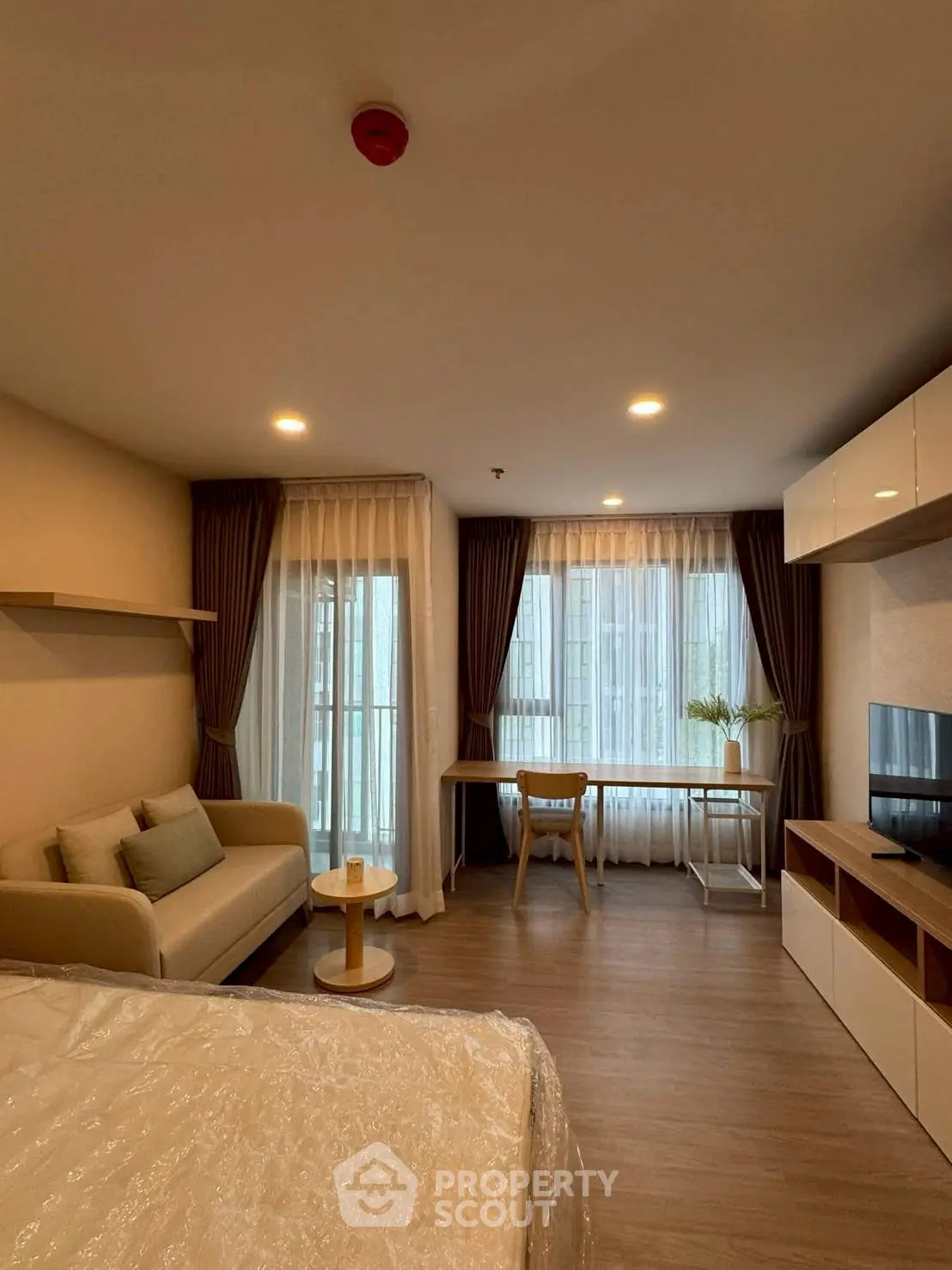 Modern studio apartment with cozy living area and large windows for natural light.