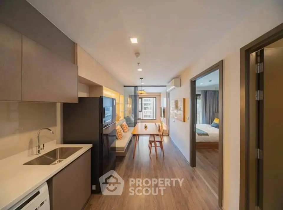 Modern open-plan apartment with sleek kitchen and cozy living area, featuring stylish decor and natural light.