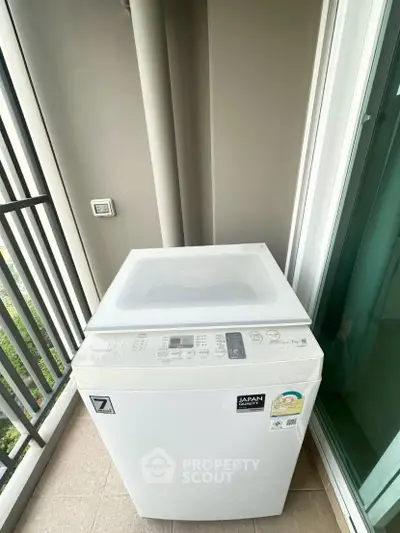 Modern washing machine on a balcony with sleek design and city view.