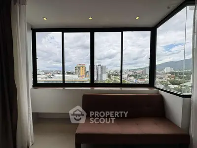 Stunning cityscape view from modern apartment window with cozy seating area.