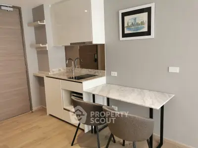 Modern compact kitchen with sleek cabinetry and dining area in a stylish apartment.