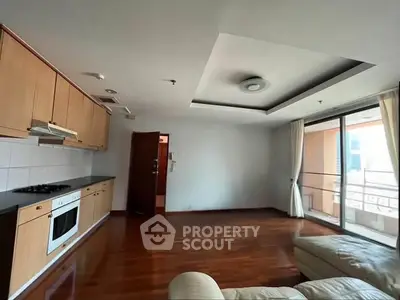Spacious living room with open kitchen and balcony access in modern apartment.