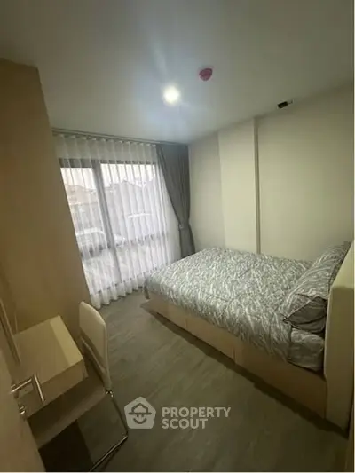 Cozy bedroom with modern furnishings and large window for natural light.