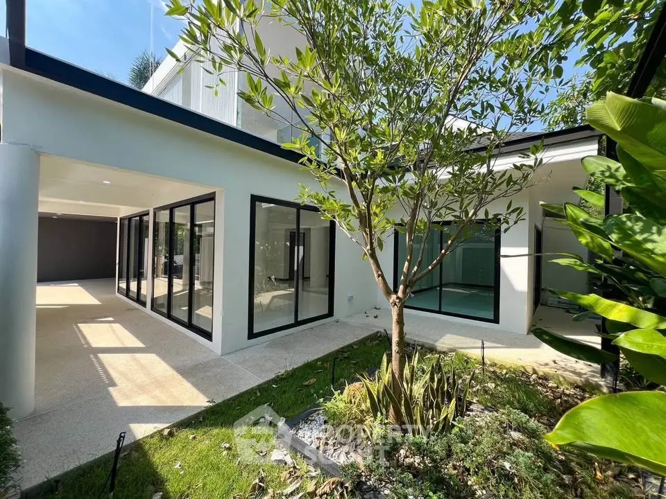 Modern architectural home with large windows and lush garden