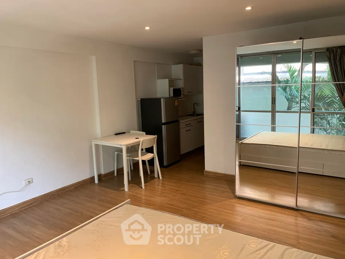 Spacious studio apartment with mirrored wardrobe and modern kitchen appliances.