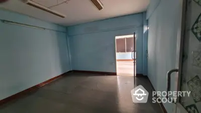 Spacious empty room with blue walls and open door leading to balcony