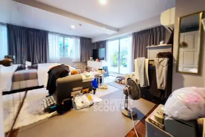 Spacious bedroom with large windows and modern decor, featuring a cozy seating area and ample natural light.