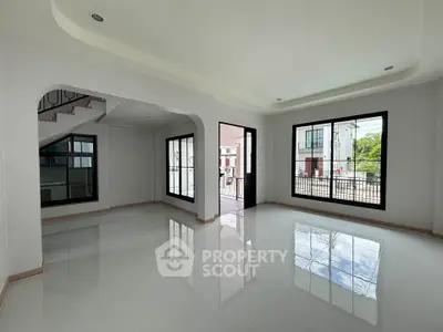 Spacious modern living room with large windows and glossy floors, offering abundant natural light and a sleek design.