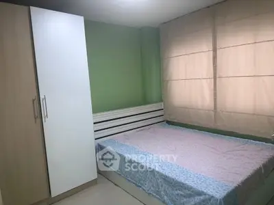 Cozy bedroom with green accent wall and ample natural light