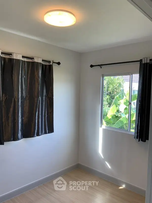 Bright room with window view and elegant curtains, perfect for a cozy study or small bedroom.