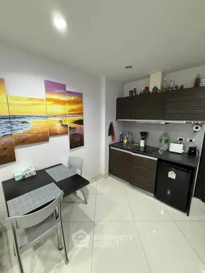 Modern kitchen with sleek cabinets and dining area, featuring vibrant wall art and compact appliances.