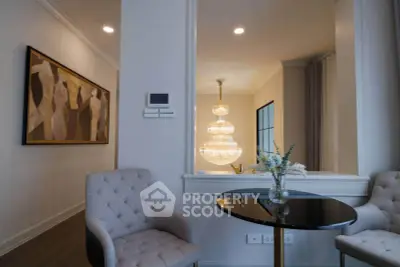Elegant living room with plush chairs, modern art, and a stunning chandelier, perfect for sophisticated living.