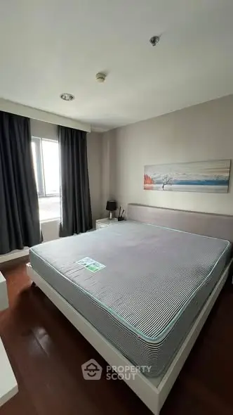 Spacious bedroom with large bed and modern decor, featuring natural light from a window.