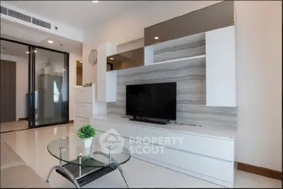 Modern living room with sleek TV unit and glass coffee table in a stylish apartment.