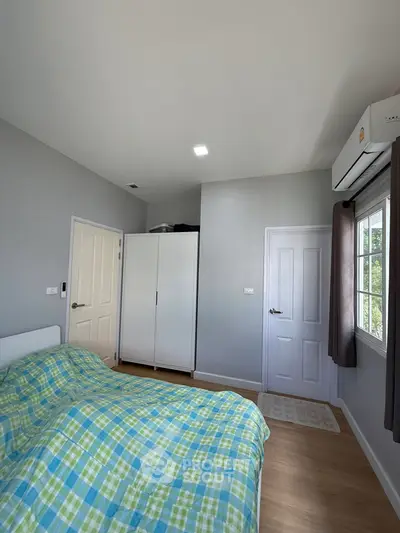 Cozy bedroom with modern decor, featuring a large window and ample storage space.