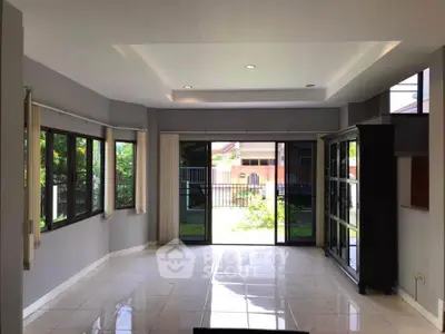 Spacious living room with large windows and garden view, perfect for natural light lovers.