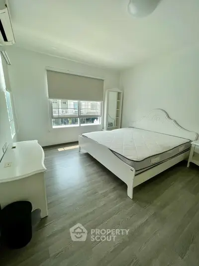 Bright and airy bedroom with elegant white furniture and large window view.