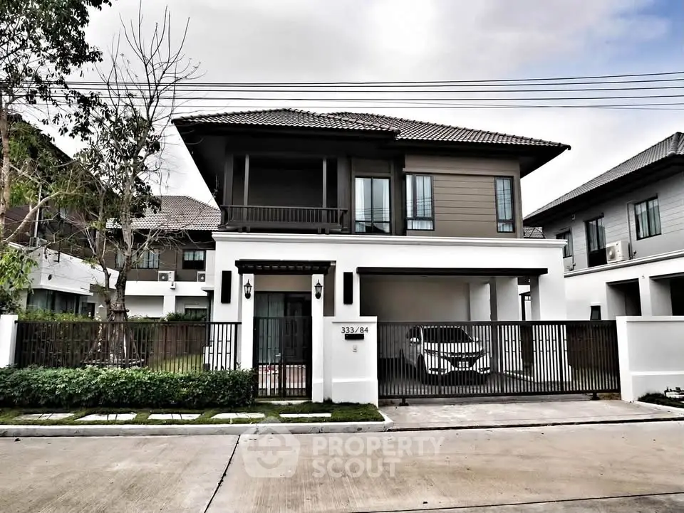 Modern two-story house with gated driveway and landscaped front yard in a suburban neighborhood.