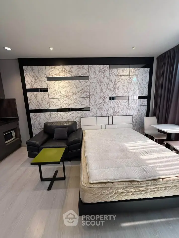 Modern studio apartment with stylish marble accent wall and cozy furnishings.