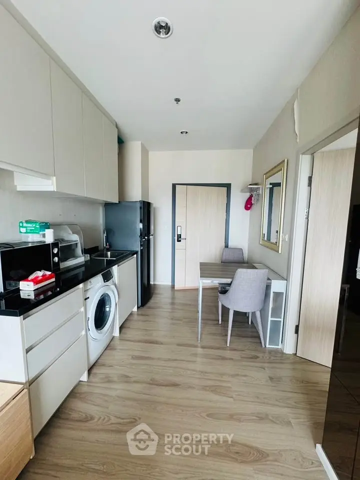 Modern kitchen with sleek appliances and dining area in stylish apartment.