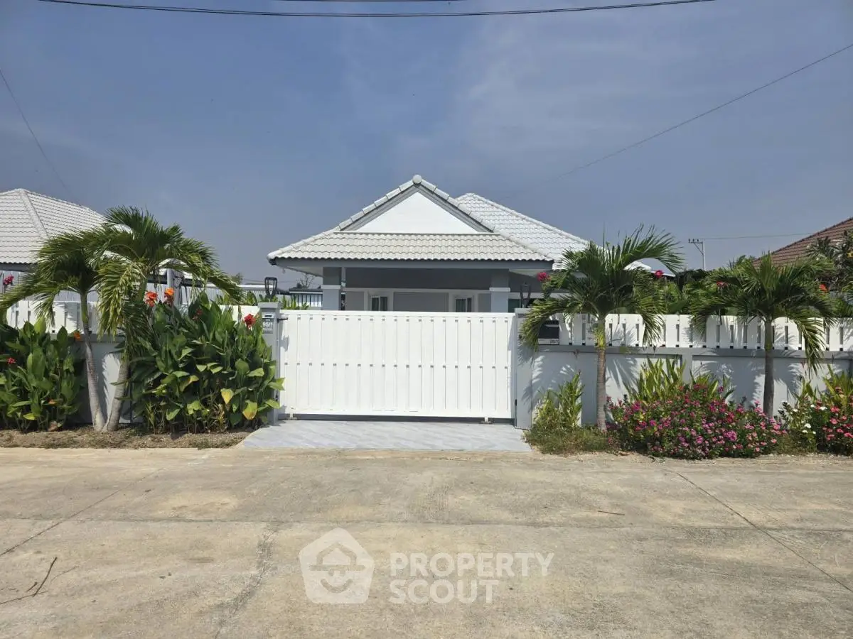 Charming single-story home with white picket fence and lush garden in serene neighborhood.