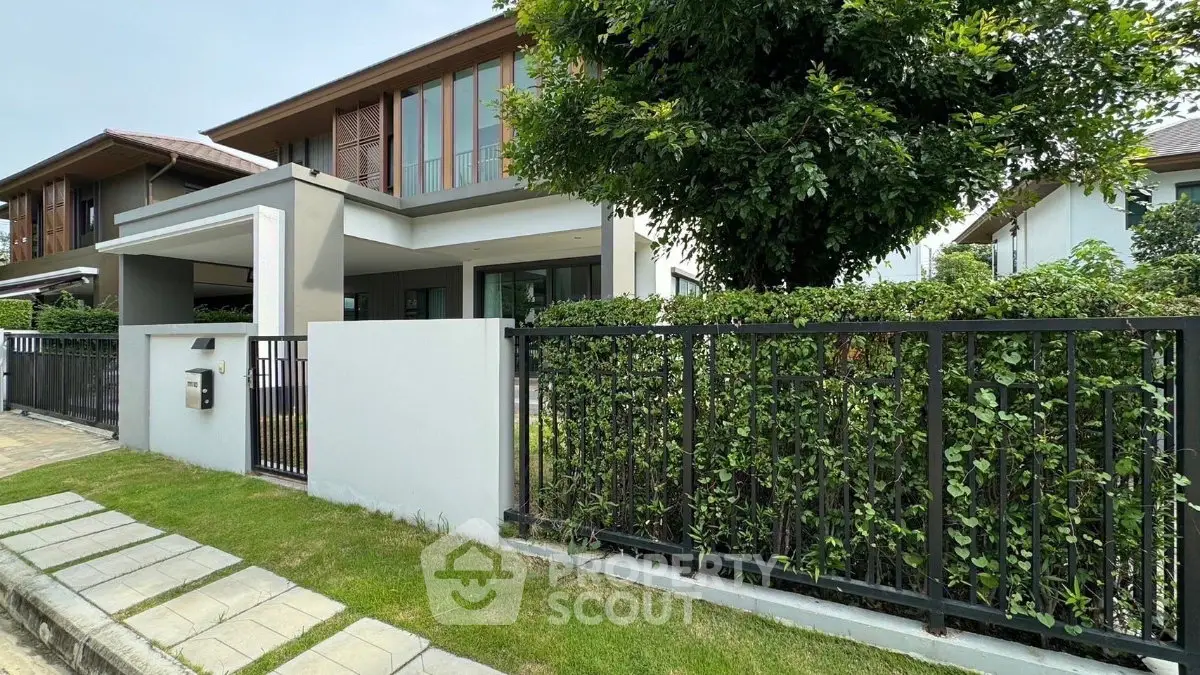 Modern suburban house with lush greenery and sleek fence, perfect for family living.