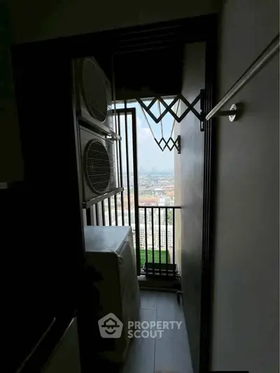 Compact balcony with laundry appliances and city view in modern apartment.